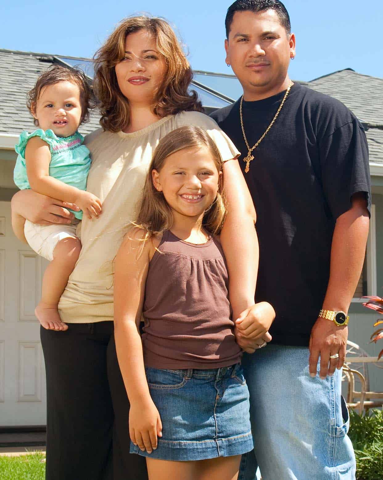 Hispanic family portrait outside their neighborhood home